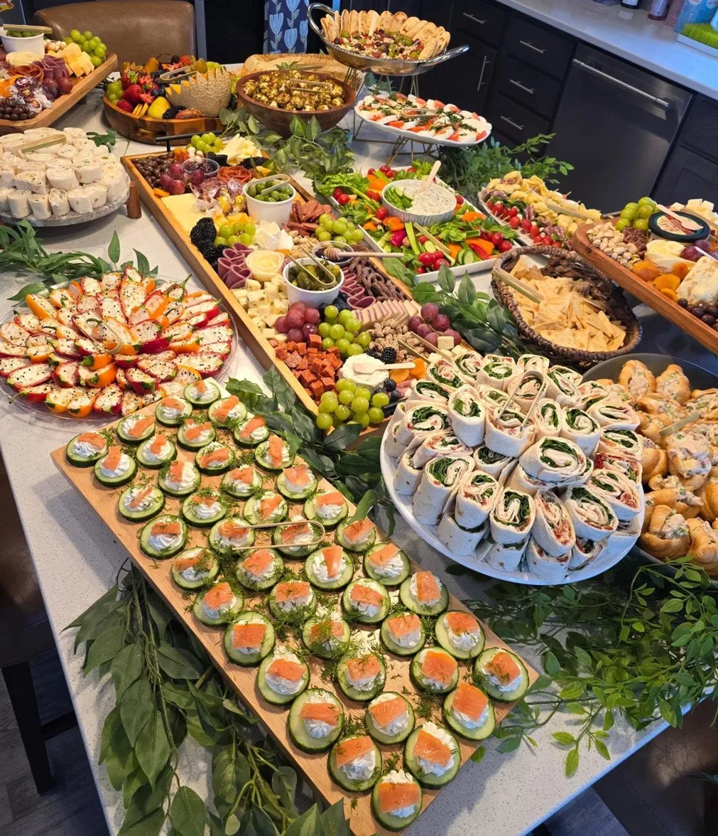 Charcuterie spread with cucumber bites, pinwheels, and fresh greens