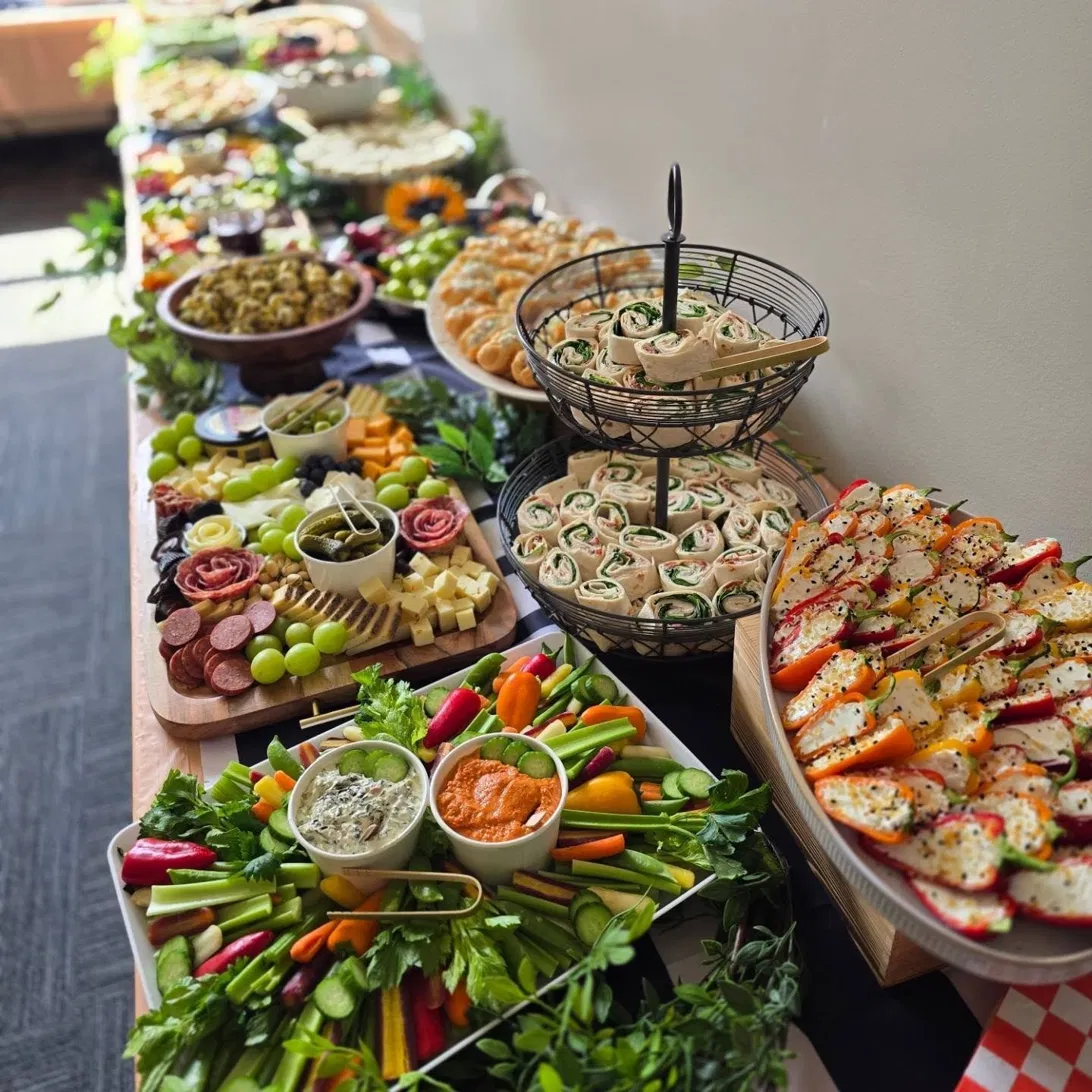 Long buffet of salads, pinwheels, and charcuterie for an event