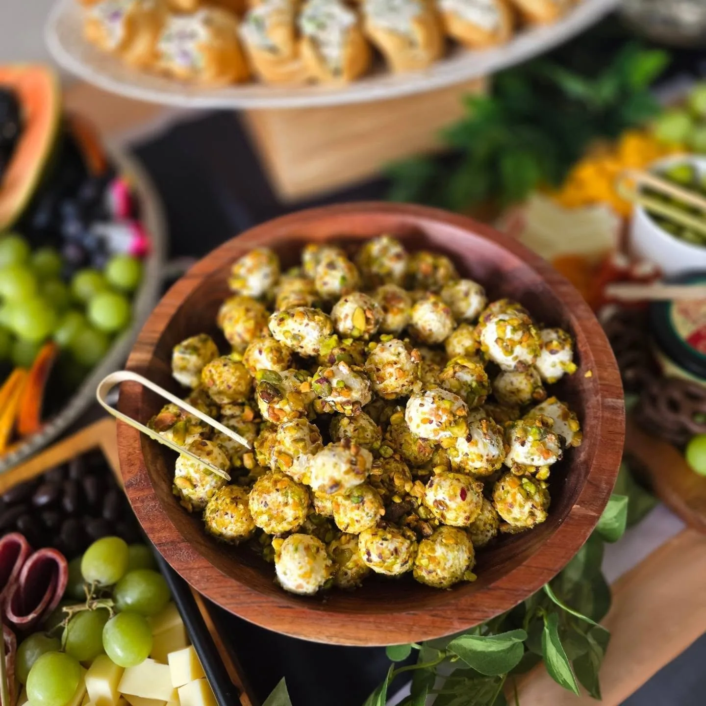 Wooden bowl of pistachio-crusted goat cheese truffles with grapes